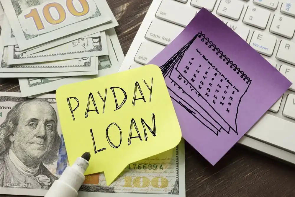 Sticky note reading "Payday Loan" atop money