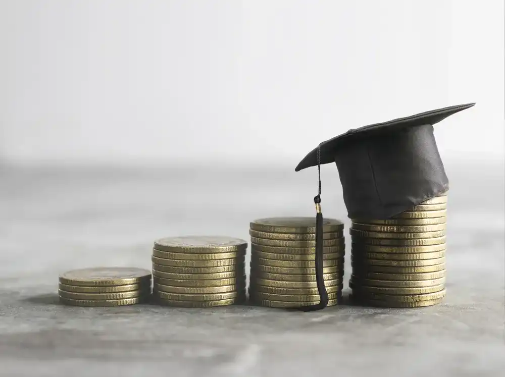 A graduation cap atop stacks of coins