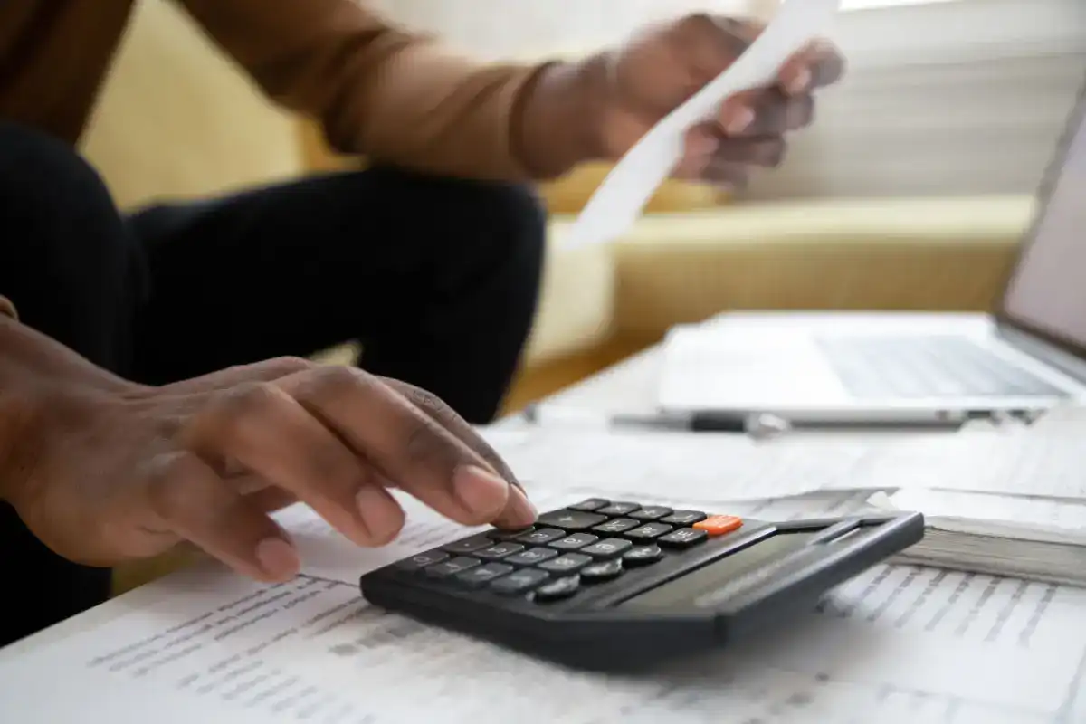 Person looking up financial terms with a laptop and calculator