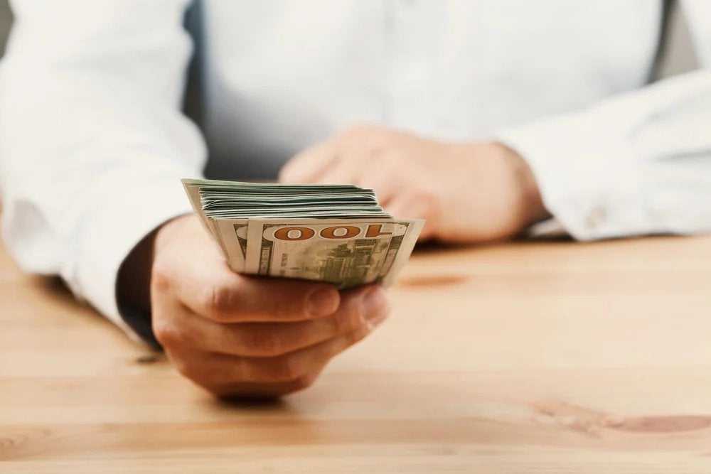 Someone holding a stack of hundred dollars bills got from a cash loan