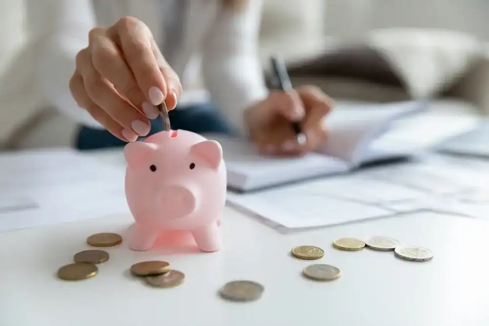 Someone saving money by putting change in a piggy bank