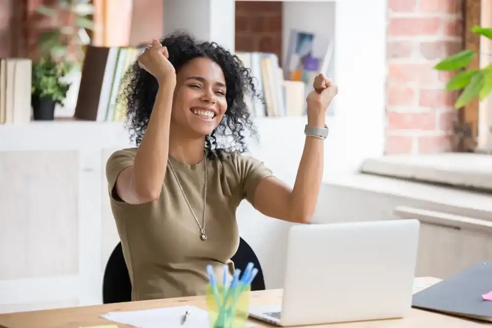 Woman celebrating on her laptop after getting a loan