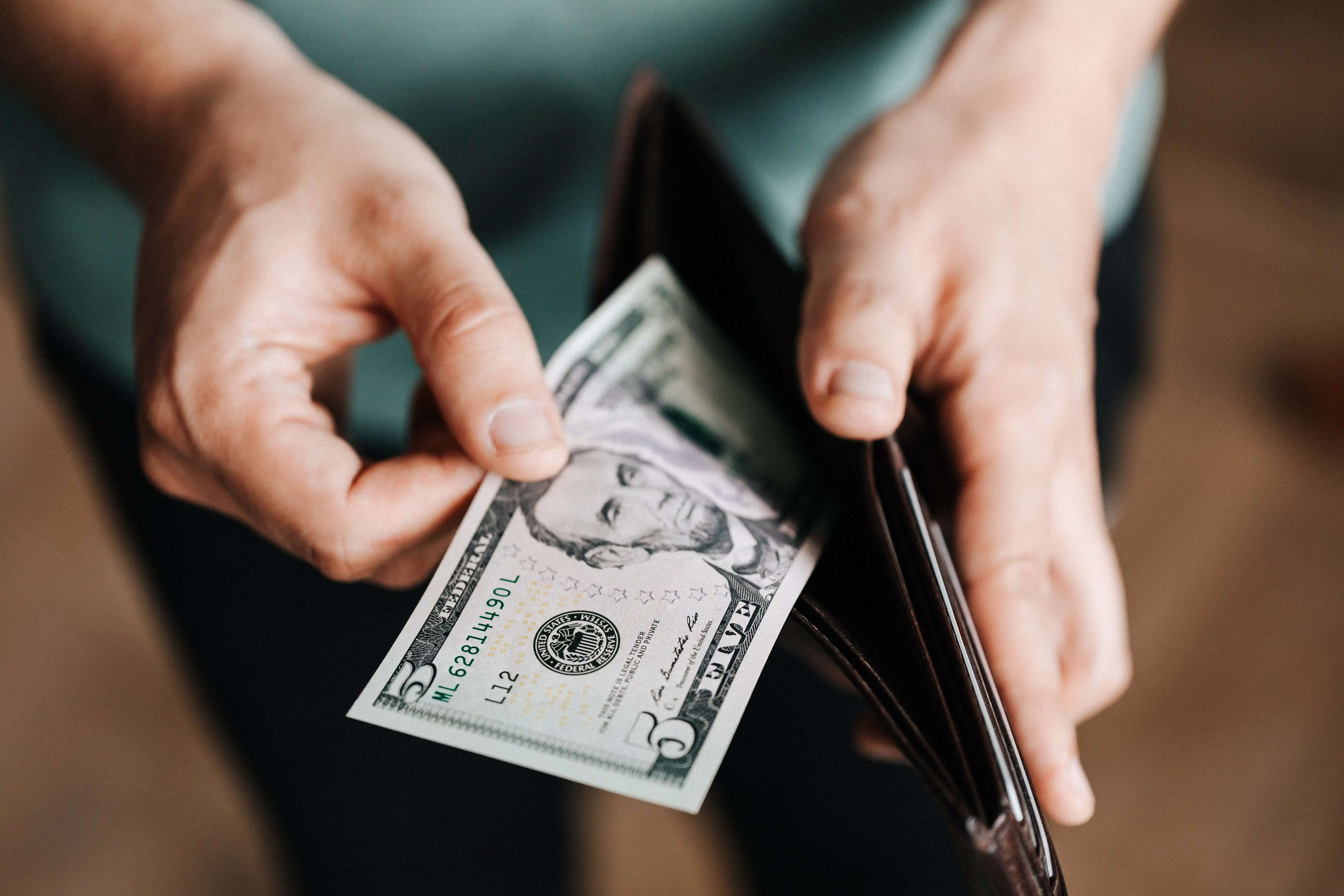 Someone paying money out of their wallet to repay their debts