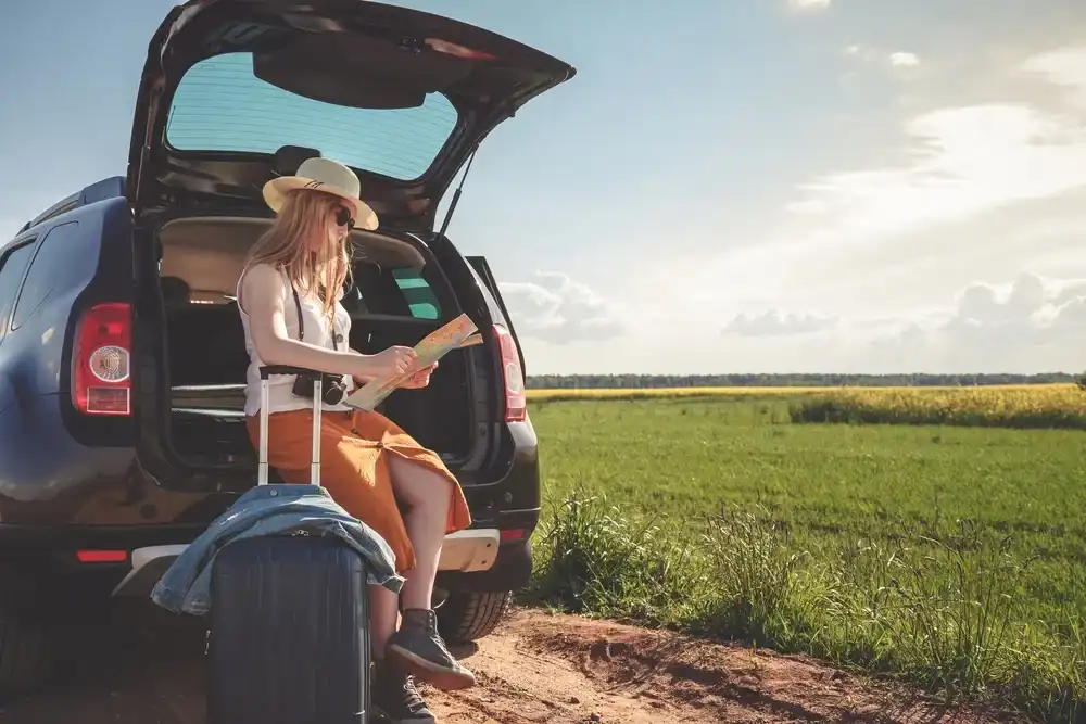 Woman sitting by her car with a map for her staycation