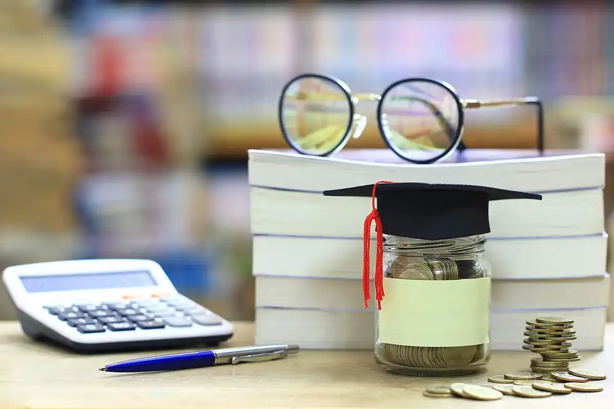 A jar of change and glasses next to financial books