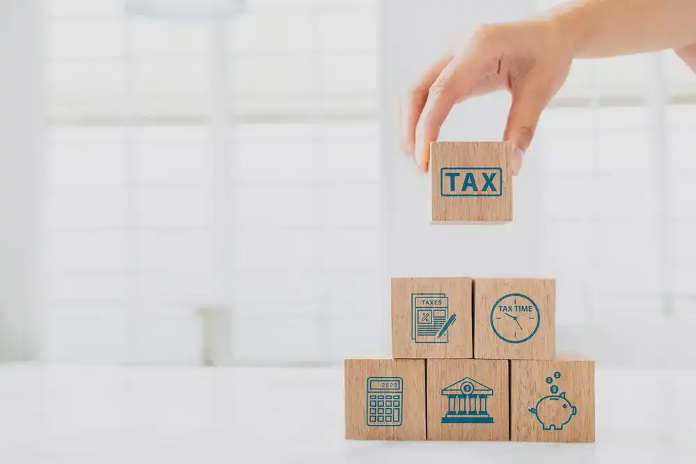 Someone placing a block that reads "Tax" atop other symbols representing check cashing services