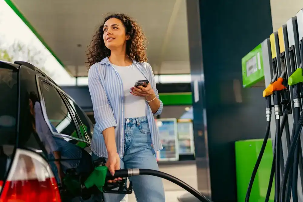 A woman paying for gas at the pump on her phone
