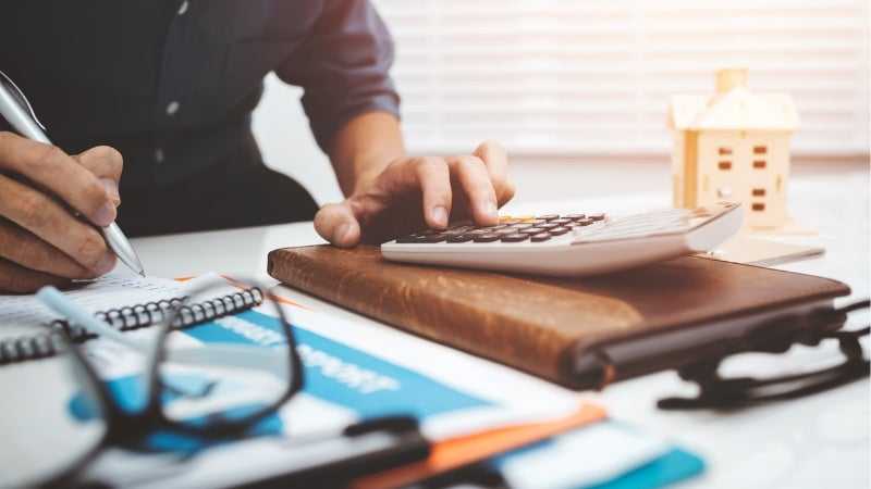 Man using a calculator to budget for a vacation he will pay for with an installment loan