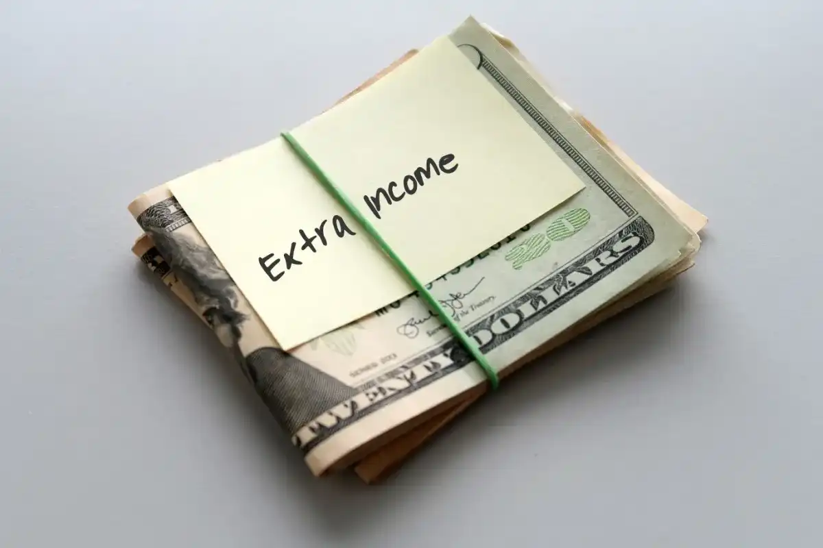 Wad of money with a sign that says "Extra Income" on top