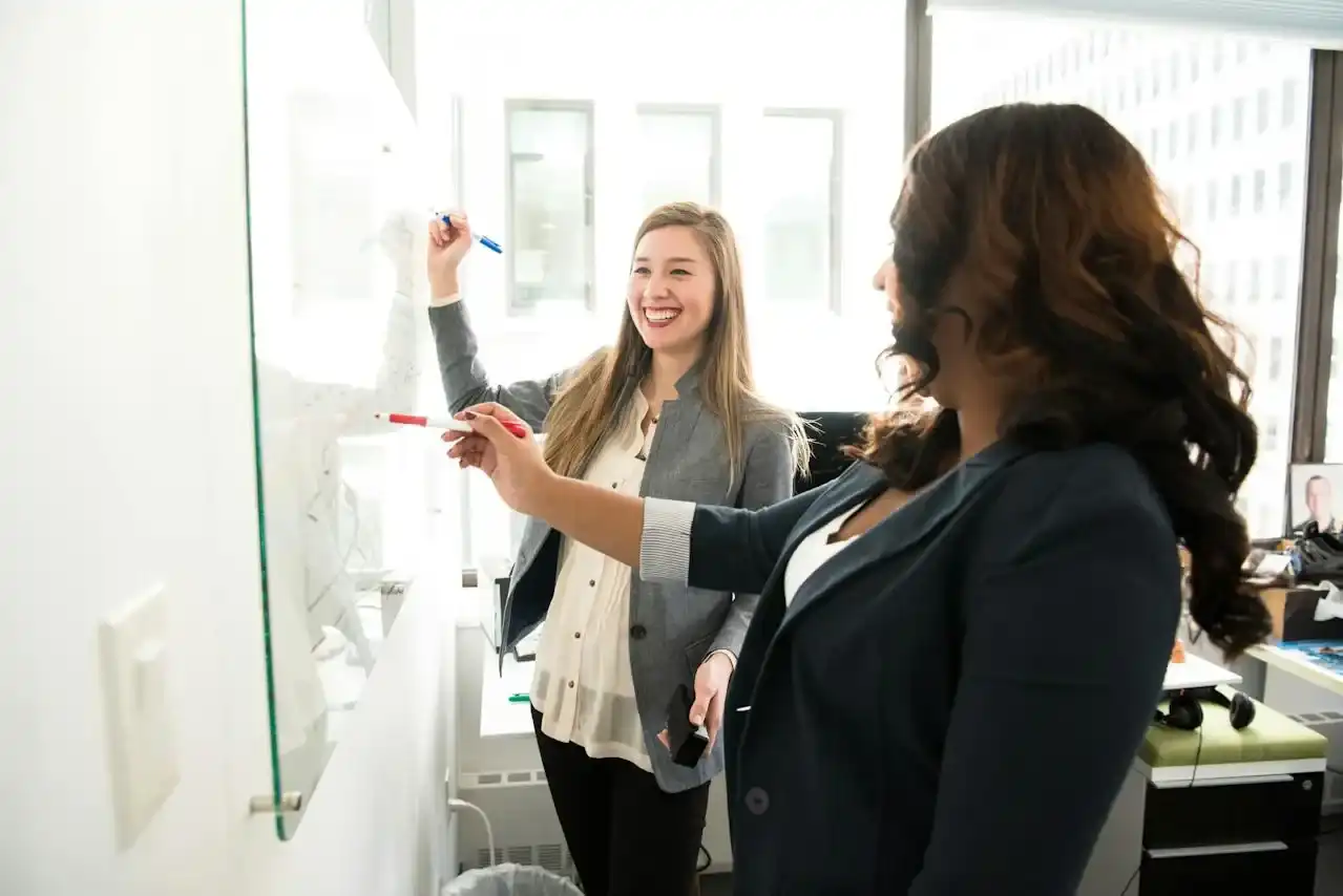 Two women manifesting financial success with a vision board