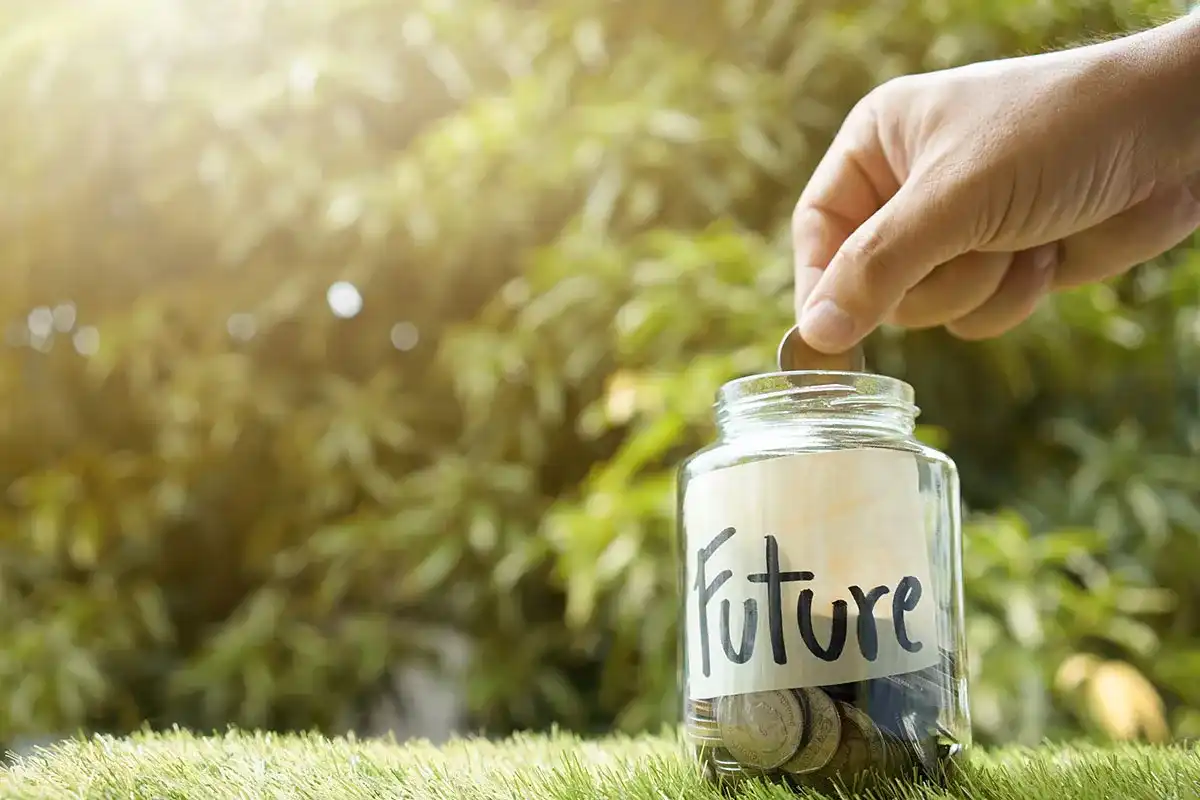 Person putting change into a jar with "Future" on it, representing wealth planning
