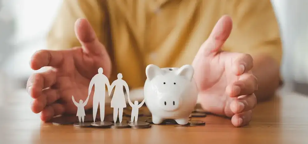 A paper family next to a piggy bank