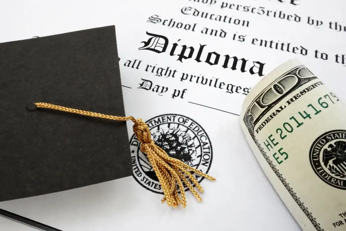 A diploma with cash on top of it, representing different student loan options
