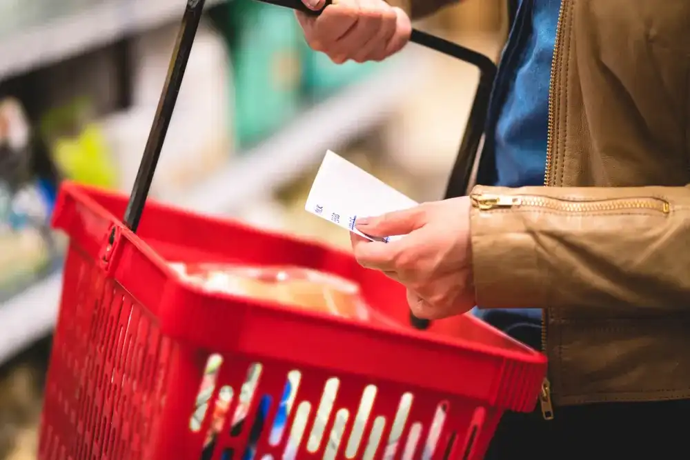 Person at the grocery store with a budget friendly food list