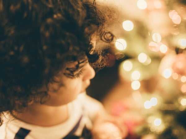 Child standing by a Christmas tree 