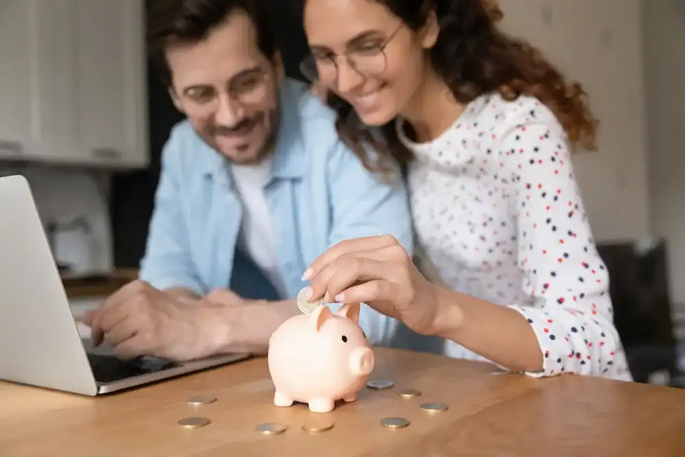 A couple depositing money into their piggy bank from a cashed check