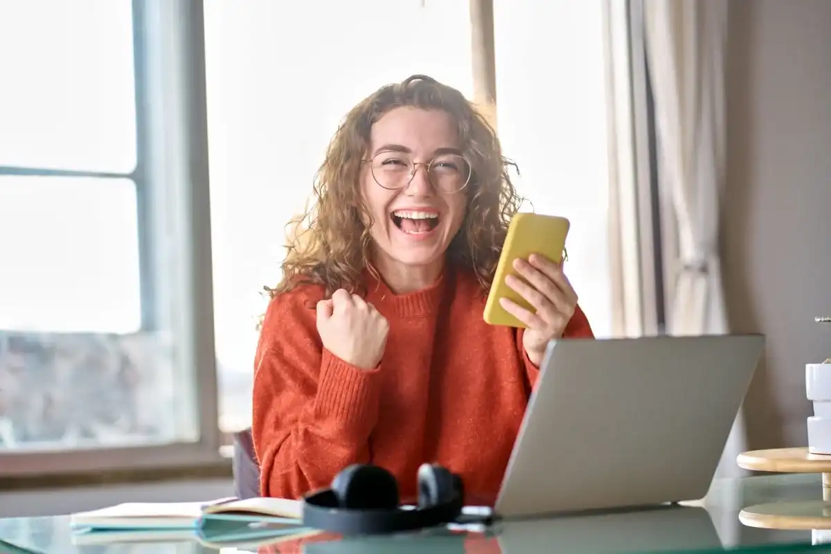Woman smiling with her phone after paying off credit card bills