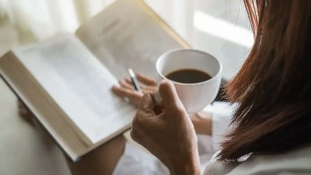 Woman enjoying her coffee with a top financial book of 2023