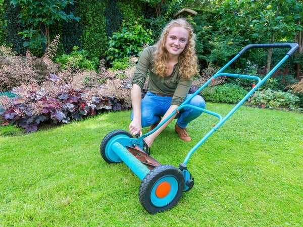 Woman using a push reel mower to mow her yard 