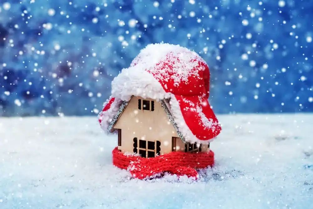 Wooden house model covered in winter clothing in the snow