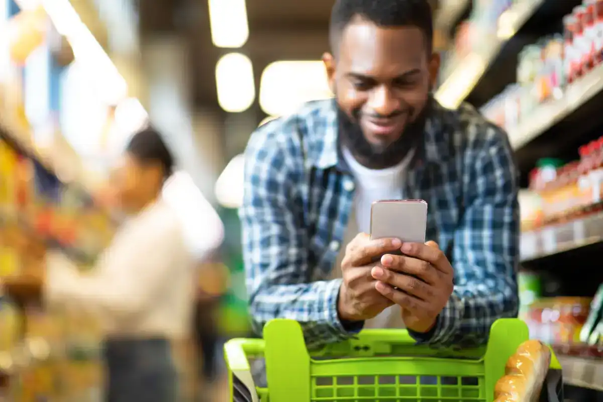 Man saving money at the grocery store with a mobile app
