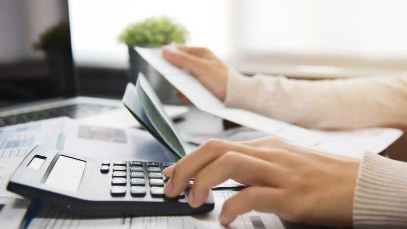 Woman using a calculator to refinance her installment loan 