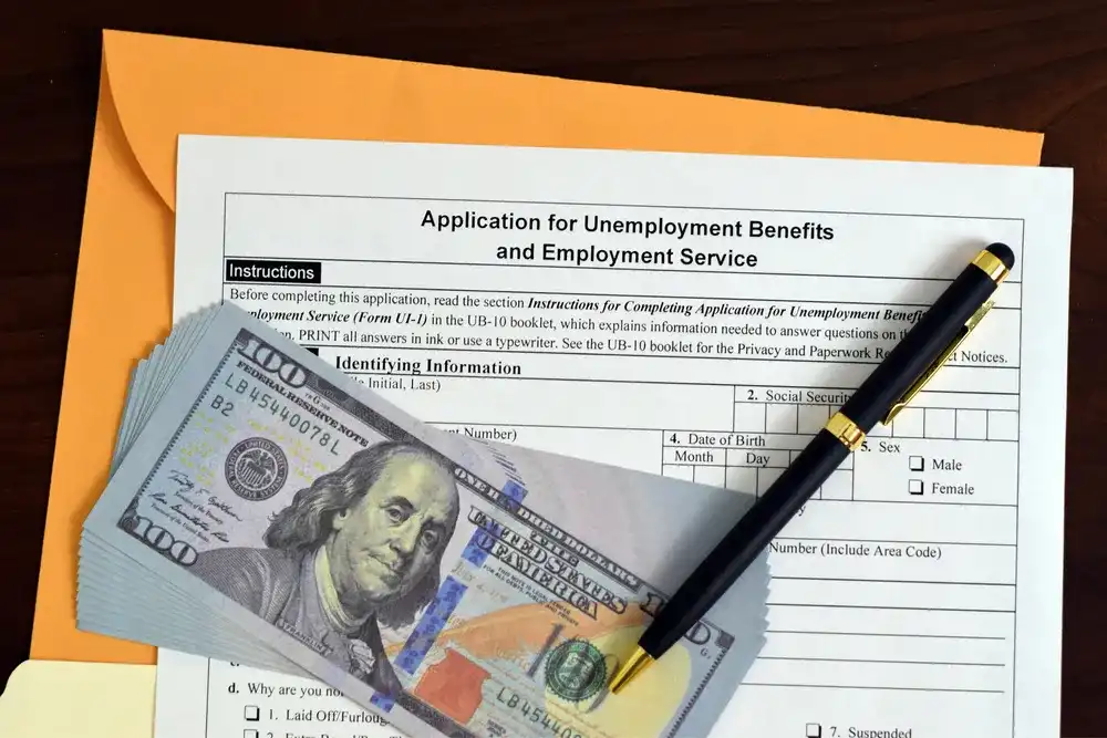$100 bills on top of an application for unemployment benefits and employment service